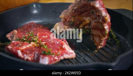 Appetitliches Rindersteak in einer Pfanne, gewürzt mit Kräutern. Kochen Kunst Essen Fleisch Essen Lecker Stockfoto