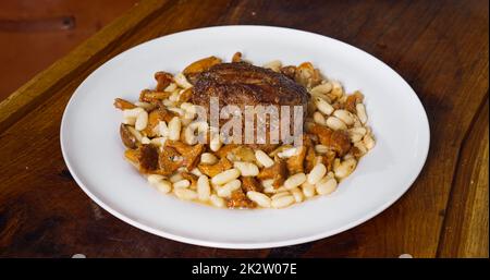 Professioneller Koch kocht in der Küche. Leckeres Gericht mit Rindersteak und Bohnen. Stockfoto