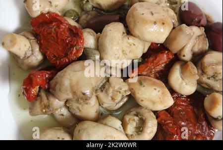 Pilze, sonnengetrocknete Tomaten, Oliven und Kapern in Olivenöl Stockfoto