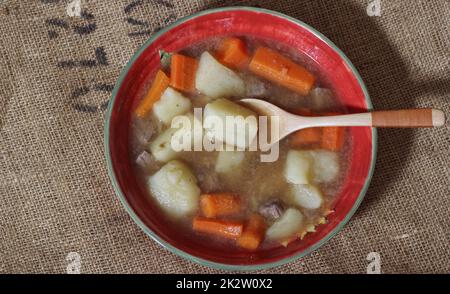 Herzhafter Rindereintopf mit Kartoffel und Karotten auf Vintage Burlap Kartoffelbeutel Stockfoto