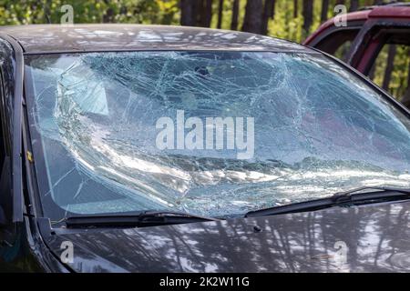 Nahaufnahme eines Autos mit gebrochener Windschutzscheibe nach einem Unfall. Gefahr durch Kraftfahrzeuge. Leichtsinniges, gefährliches Fahren. Ein Auto nach einem tödlichen Unfall mit einem Fussgänger. Ukraine, Irpen - 12. Mai 2022. Stockfoto