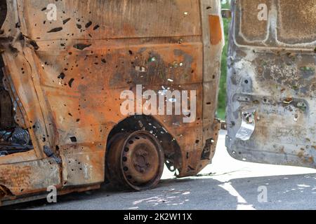 Verbrannte Autokarosserie voller Kugeln. Russlands Krieg gegen die Ukraine. Erschossen vom russischen Militärauto von Zivilisten während der Evakuierung. Spuren von Kugeln und Muschelfragmenten. Stockfoto