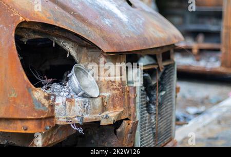 Das Auto wurde durch Feuer zerstört. Verlassenes, verbranntes und rostiges Auto an der Straße. Die Autos brannten auf dem Parkplatz. Krieg Russlands gegen die Ukraine. Schrapnell und Einschusslöcher in Autos. Stockfoto