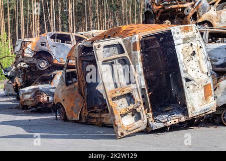 Autos nach dem Feuer. Eisenteile eines verbrannten Autos. Ausgebrannte Autos, die auf einer ruhigen Landschaft stehen. Explosion, die Folge eines Brandes. Kfz-Versicherungskonzept. Krieg Russlands gegen die Ukraine. Stockfoto