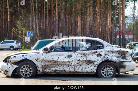 Erschossen, beschädigte Autos während des Krieges in der Ukraine. Das Fahrzeug der von den Händen des russischen Militärs betroffenen Zivilisten. Schrapnell und Einschusslöcher in der Karosserie des Autos. Krieg Russlands gegen die Ukraine. Stockfoto