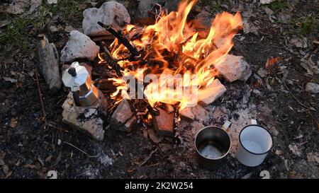 Lagerfeuer im Touristenlager in den Bergen. Wunderschönes Lagerfeuer, brennendes Holz am Sommerabend. Aktives Lifestyle-, Reise-, Wander- und Campingkonzept. Lagerfeuer brennt in Zeitlupe Stockfoto