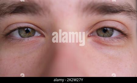 Nahaufnahme von Männergesicht. Attraktiver Junge, seine schönen grünen Augen. Europäisches junges männliches Modell, das auf die Kamera schaut. Extrem Stockfoto