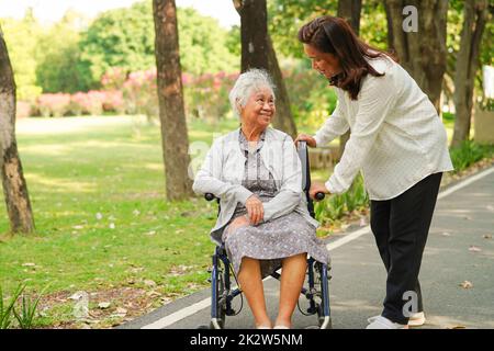 Pfleger helfen und unterstützen asiatische ältere oder ältere alte Dame Frau Patientin im Rollstuhl im Park, gesund starke medizinische Konzept. Stockfoto