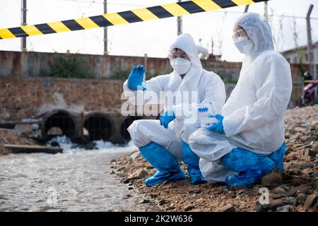 Ökologe, die Wasser aus dem Fluss mit einem Reagenzglas entnehmen Stockfoto