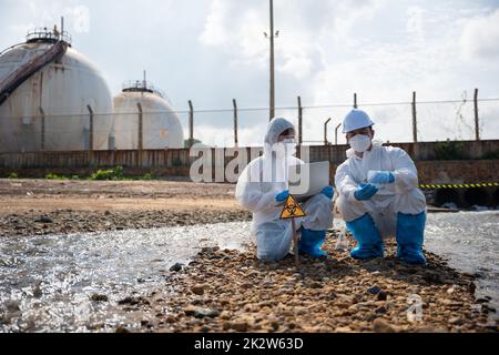 Biologe tragen Schutzanzug und Maske sammelt Abwasserproben aus der Industrie Stockfoto