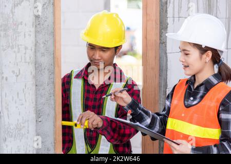 Männliche industrielle Bauarbeiter Verlegeprozess Holztür mit Maßband messen Stockfoto