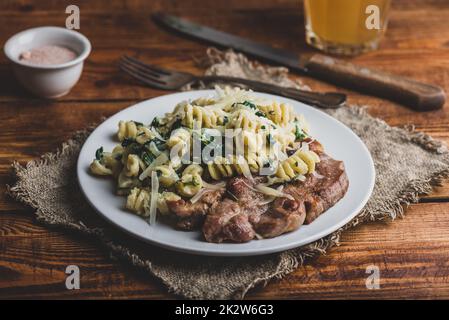 Schweinesteak und cremige Spinatpasta Stockfoto