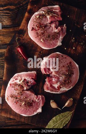 Raw Schweinelende Steaks mit verschiedenen Gewürzen Stockfoto