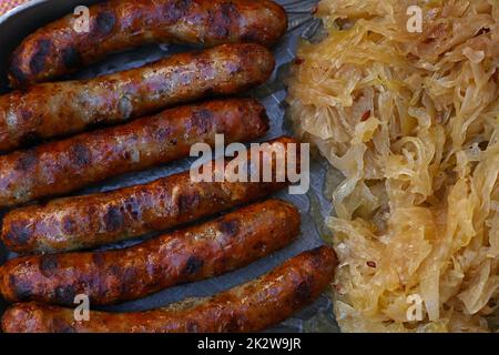 Close up Teil der gegrillten Nürnberger Bratwurst Bratwurst mit Beilage von Sauerkraut auf Metall Zinnteller, Erhöhte Ansicht von oben, direkt über Stockfoto