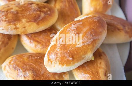 Viele leckere, frisch gebackene heiße Kuchen mit Füllung, Essenshintergrund, Nahaufnahme, russische Küche Stockfoto