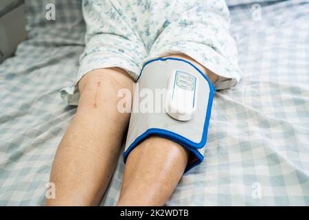 Ältere oder ältere asiatische Patientin mit schnurloser Luftkompression – Beinmassage auf dem Bett im Pflegekrankenhaus. Stockfoto