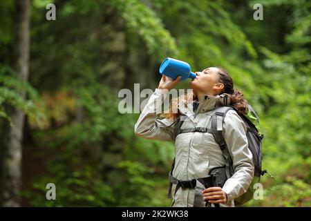 Trekker trinkt Wasser aus der Kantine im Wald Stockfoto