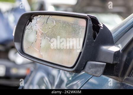 Nahaufnahme eines gebrochenen linken Rückspiegels eines Autos in Blau. Kfz-Versicherungskonzept. Zerbrochene Seitenscheibe des Fahrzeugs auf der Fahrerseite als Folge eines Unfalls. Krimineller Zwischenfall. Stockfoto