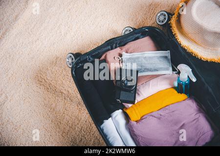 Offener Koffer mit persönlichen Gegenständen von Reisenden, Kleidung und Accessoires für die Sommerferien Stockfoto