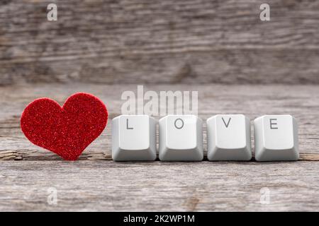 Rotes Herz und WORTLIEBE auf Tastaturtasten geschrieben Stockfoto
