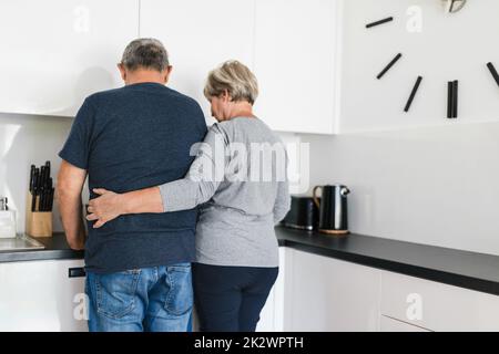 Glückliches romantisches Seniorenpaar, das zu Hause gerne kocht Stockfoto
