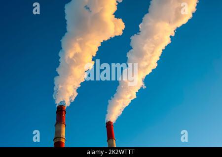 Weißer Rauch kommt aus den Rohren am blauen Himmel Stockfoto