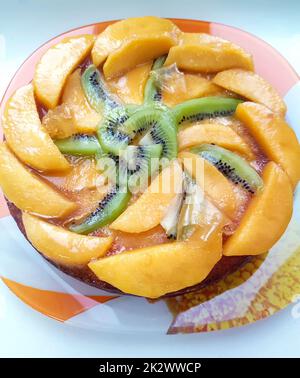 Glasierte Obstkuchen oder Torte mit geschnittener Kiwi-Frucht und Pfirsich, Draufsicht Stockfoto