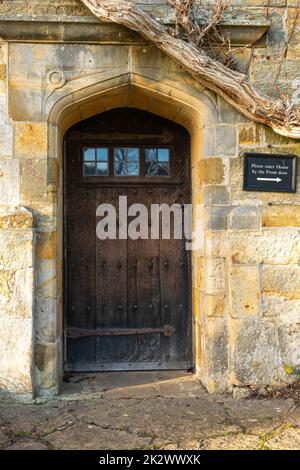 Alte Eichentür mit kleinen Fenstern in einer Steintür, Bateman's, Burwash, East Sussex, England Stockfoto