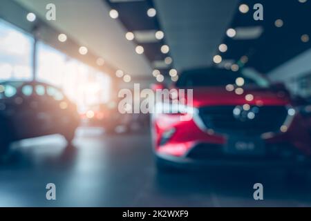 Verschwommenes Foto neuer roter Wagen im Ausstellungsraum geparkt. Büro des Autohändlers. Das Auto wurde mit Sorgfalt im Ausstellungsraum geparkt. Autovermietung und -Verkauf. Automobilleasing-Markt. Elektrofahrzeug. Automobilindustrie. Stockfoto