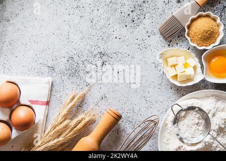 Hintergrundrahmen für Backen oder Kochen. Zutaten, Küchenartikel zum Backen von Kuchen. Küchenutensilien, Mehl, Eier, brauner Zucker, Butter. Textbereich, Draufsicht. Kekse Pie Oder Kuchenrezept Modell Stockfoto