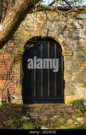 Große schwarze Tür in einem alten Steineingang, Bateman's, Burwash, East Sussex, England. Stockfoto