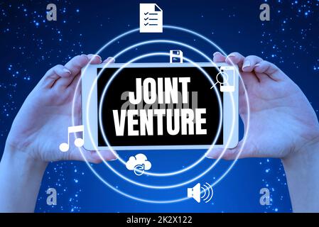 Text zeigt Inspiration Joint Venture. Ein Wort, das in den Händen des Partnerschaftsteams von Collaboration Arrangement Parties geschrieben wurde und innovative Ideen präsentiert, die Technologie symbolisieren. Stockfoto