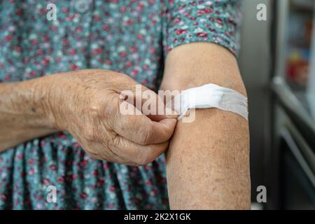 Asiatische Seniorin oder ältere Frau Patient zeigen Baumwolle Wolle stoppen Blutungen, nach Blutentnahme Tests für jährliche körperliche Gesundheitsprüfung, um Cholesterin, Blutdruck und Zuckerspiegel zu überprüfen. Stockfoto