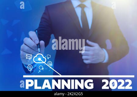 Schreiben mit Anzeige des Textes „Planning“ 2022. Wort für Anfang mit Ende in der Vorstellung Positionierung langfristige Ziele man-Hold-Bildschirm des Mobiltelefons mit der futuristischen Technologie. Stockfoto