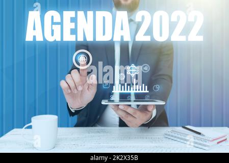 Inspiration mit Schild Agenda 2022. Internet-Konzept Liste der Aktivitäten, nach deren Aufnahme man-Hold-Bildschirm des Mobiltelefons mit der futuristischen Technologie. Stockfoto