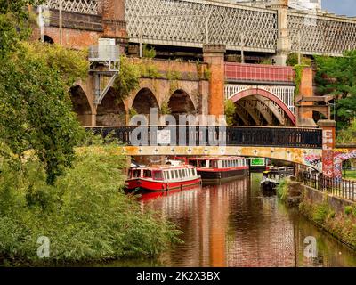 Fußgängerbrücke über den Bridgewater-Kanal mit Castlefield und Bridgewater-Viadukt in der Ferne. Manchester. VEREINIGTES KÖNIGREICH Stockfoto