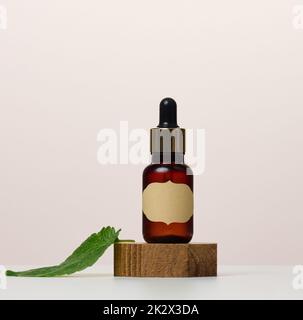 Eine braune Glasflasche mit einem Papieretikett und einer Pipette auf einem weißen Tisch. Behälter für Kosmetika Stockfoto