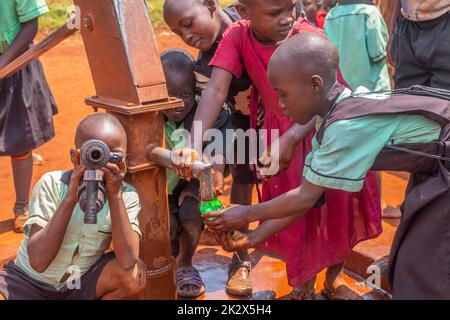 In Uganda versuchten Kinder in unterschiedlichen Alters, Trinkwasser zu sammeln Stockfoto