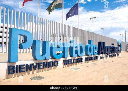 Das Begrüßungslogo von Puerto de Algeciras (Hafen von Algeciras) mit Fahnenmasten dahinter, das sich in der Nähe des Hauptfußeingangs für Passagiere befindet. Stockfoto