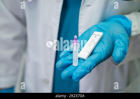 Asiatischer Arzt im PSA-Anzug mit Speichelantigen-Testkit zur Kontrolle des Covid-19-Coronavirus im Krankenhaus. Stockfoto