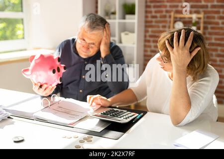 Schockiertes Paar, Das Piggybank Hält Stockfoto