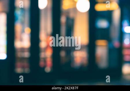Abstraktes, verschwommenes Bild eines Cafés oder Restaurants mit Bokeh-Lichtern am Abend. Stockfoto