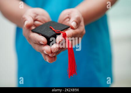 Asiatische Frau Arzt hält Abschlusshut im Krankenhaus, Medizinische Ausbildung Konzept. Stockfoto