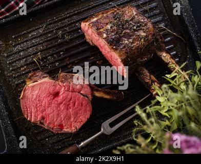 Gegrilltes Stück Fleisch mit Knochen in einer Grillpfanne. Gebratenes Steak. Rösten – Mittel Selten Stockfoto