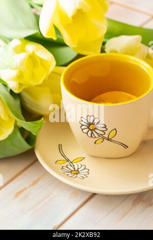 Teetasse mit Still Life und Strauß aus gelben Tulpen, weißer Stoff Stockfoto