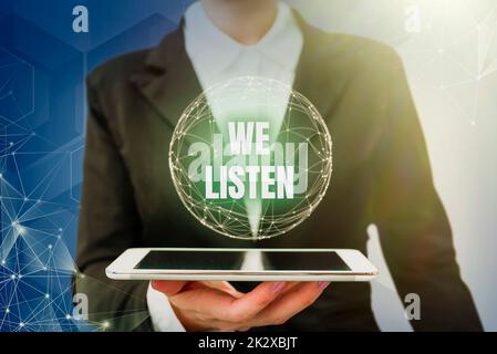 Textzeichen mit „We Listen“ (Wir hören). Business Idea Group, die zeigt, dass sie bereit ist, alles zu hören, was Sie sagen möchten. Lady im Anzug hält ein Tablet und symbolisiert globales innovatives Denken. Stockfoto