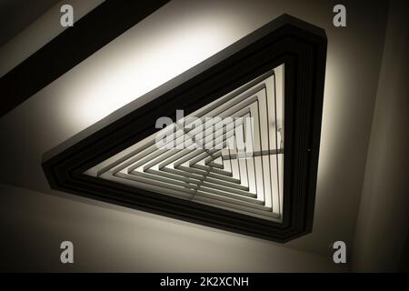 Dreieckige Lichtquelle. Leuchte im Innenraum. Designerleuchte. Architekturdetails. Stockfoto