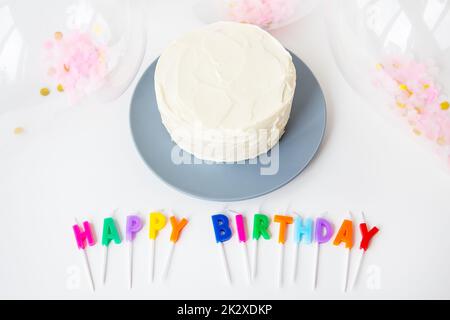 Farbenfrohe Kerzen mit Schriftzug Happy Birthday isoliert auf weißem Hintergrund zusammen mit Konfetti und Bento-Kuchen. Urlaub- und Überraschungskonzept. Stockfoto