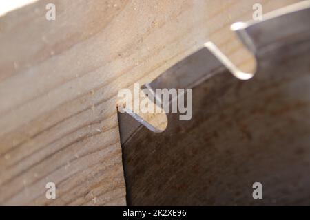Ein Stück Holz liegt am Sägeblatt einer Kreissäge an Stockfoto