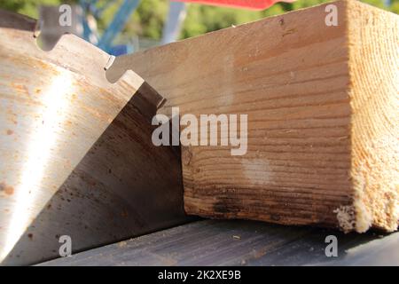 Ein Stück Holz liegt am Sägeblatt einer Kreissäge an Stockfoto